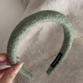 Detail showing the green wool blend fabric texture and Handmade label on the padded headband - Green