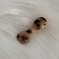 Macro shot of tortoiseshell acetate bow hair clip with gold logo on white plush surface - Light Tortoiseshell