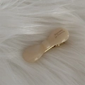 Close-up of cream acetate bow hair clip with gold metal teeth on white faux fur - Off-white