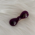 Close-up of a glossy purple bow barrette with gold lettering on a soft white fur backdrop - Purple