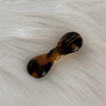 Detail of tortoiseshell acetate hair clip with gold lettering on white plush background - Dark Tortoiseshell