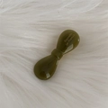 Detail of an olive green acetate bow hair clip with gold logo on a plush white background - Green