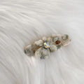 Close-up of marble acetate flower hair clip with rhinestone and metal spring detail - White Green