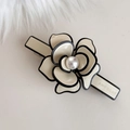 Dettaglio del fermaglio a camelia con petali crema bordati di nero e perla centrale - Fiore in Acetato Bianco Latte - Base Stretta