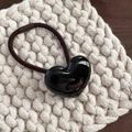 Macro shot of minimalist glossy resin heart charm on elastic hair tie for women - Black