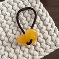 Dettaglio di un ciondolo a cuore in resina gialla su un elastico per capelli nero ad alta elasticità - Giallo