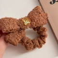 Detailansicht eines braunen Fleece-Haargummis mit einer goldenen quadratischen Smile-Schnalle - Smiley Hellkaffee Haargummi