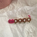 Detail of pink cartoon cat hair clip with soft flocked texture and green feet accents - Long Cat - Caterpillar Style