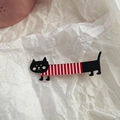Dettaglio di una spilla a forma di gatto nero lungo con strisce rosse e bianche su carta - Gatto Lungo - Vestiti a Righe Rosse