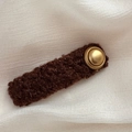 Macro shot of a coffee-colored lamb wool hair clip with a vintage matte gold button detail - Rectangle / Brown