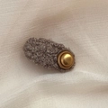 Nahaufnahme der braunen Fleece-Haarspange mit einem eleganten runden goldenen Metallknopf - Oval / Khaki