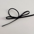 Dettaglio di elastico per capelli in pelle nera con trama fine in PU e nodo a fiocco - Nero