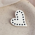Dettaglio del fermaglio per capelli a cuore bianco con pois neri su piatto di ceramica - Bianco
