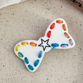 Dettaglio macro di un fermaglio a fiocco con cuciture arcobaleno e stella nera - Fiocco Cucito Bianco
