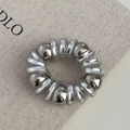 Détail d'élastique spirale argenté avec perles métalliques sur fond en toile - Perle Argentée