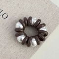 Dettaglio dell'elastico a spirale marrone caffè con perle su tessuto beige - Perla Caffè