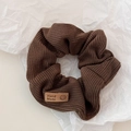 Detail of dark brown knitted scrunchie with a handmade smile patch on white texture - Dark Coffee