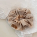 Detail of knitted hair scrunchie with smiley face patch and Hand Made leather label - Beige