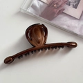 Détail d'une grande pince à cheveux à grain de bois ambré pour coiffures élégantes relevées - Café