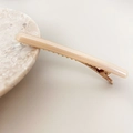 Close-up of minimalist acetate hair clip with rose gold metal base on marble - Beige