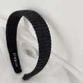 Macro shot of black knitted headband with vertical ribbed texture and brand label - Headband / Black