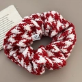 Detailed close-up of a festive red and white tweed knitted scrunchie with a logo label - Houndstooth