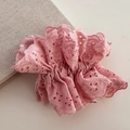 Gros plan d'un chouchou en dentelle rose avec broderie évidée et design plissé - Rose