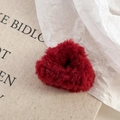 Detail eines roten Plüsch-Haargummis in Herzform mit weicher Textur auf weißem Hintergrund - Rot