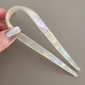 Detail of a creamy white acetate U-shaped hair pin with a pearlescent finish held by hand - Mermaid White