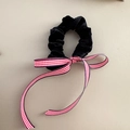 Detail view of a black velvet scrunchie featuring a classic red and white checkered ribbon bow - Black