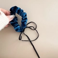Nahaufnahme eines dunkelblauen Samt-Haargummis mit schwarz-weiß gepunktetem Band - Marineblau