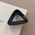 Dettaglio della pinza per capelli triangolare nera lucida con finitura brillante su beige - Nero
