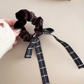Detailed macro of dark brown velvet scrunchie with classic black and white plaid ribbon bow - Brown
