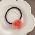 Detailed view of pink camellia floral hair tie on a white decorative ceramic tray - Watermelon Red
