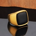 Detailed close-up of a men's gold signet ring with a matte black stone inlay on mirror - Gold Black Agate