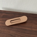 Detailed view of matte brown alloy hair clip on a natural wood grain surface - Brown