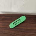 Detail of a minimalist matte green oval hair clip with a geometric cutout on wood surface - Green