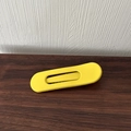 Detail view of a matte yellow alloy hair clip with a hollow rectangular design on wood - Yellow