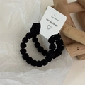 Close-up of two black textured knit hair ties with decorative heart patterned tags - Black