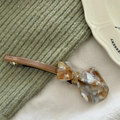 Detail of handmade acetate hair clip featuring a 3D bow design in tortoiseshell finish - Coffee & Orange