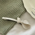 Close-up of cream marble textured acetate bow hair clip on a white ceramic plate - Off-white