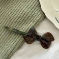 Detail of a handmade acetate bow hair clip with tortoiseshell texture on knit fabric - Blue Coffee
