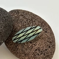 Dettaglio della molletta ovale verde con griglia nera e testo France Handmade inciso - Griglia Blu - Fermaglio a Becco d'Anatra Ovale