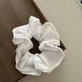 Detailed shot of a white textured fabric scrunchie resting on a dark wood tray - White
