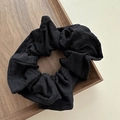 Macro detail of black waffle texture fabric scrunchie on a minimalist wooden tray - Black