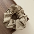 Detailed close-up of khaki scrunchie with dashed embroidery on cotton-linen fabric - Brown