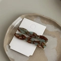 Detail of twisted acetate hair clips with retro marble patterns on a ceramic tray - Green & Brown