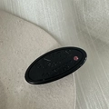 Detailopname van de zwarte ovale haarclip met SAVON-tekst en een roze strassteen - Zwart