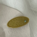 Macro-opname van olijfgroene hars haarclip met SAVON tekst en blauw kristal detail - Geel