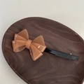 Detalle de la pinza para el pelo con lazo caramelo y logotipo de France Handmade - Lazo de Gelatina Etiqueta Dorada-Naranja